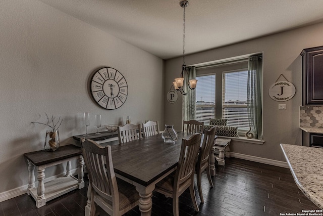 dining space featuring dark wood-type flooring and a notable chandelier