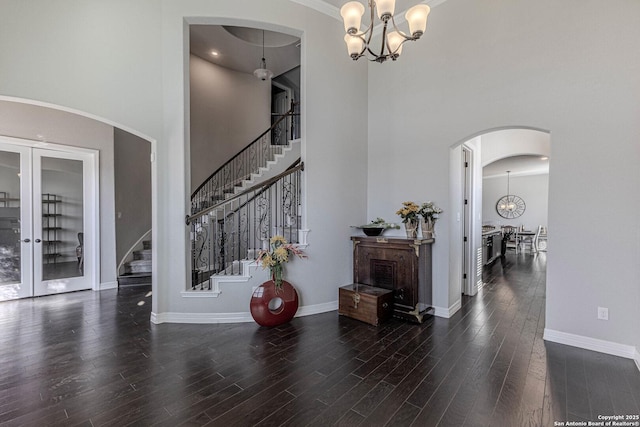 foyer entrance with a high ceiling, dark wood-type flooring, french doors, and a notable chandelier