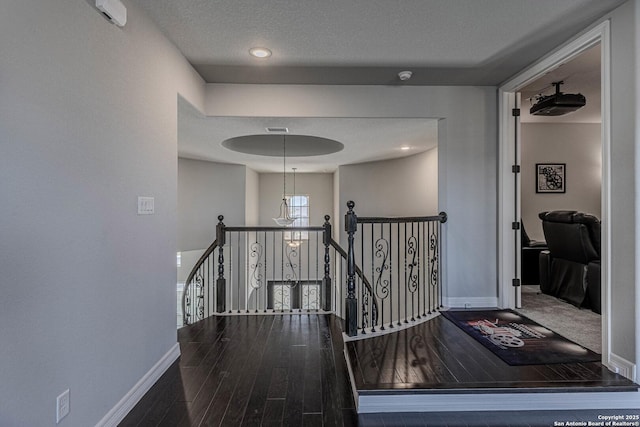 hall featuring hardwood / wood-style flooring, a textured ceiling, and a notable chandelier