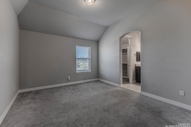 carpeted spare room featuring lofted ceiling