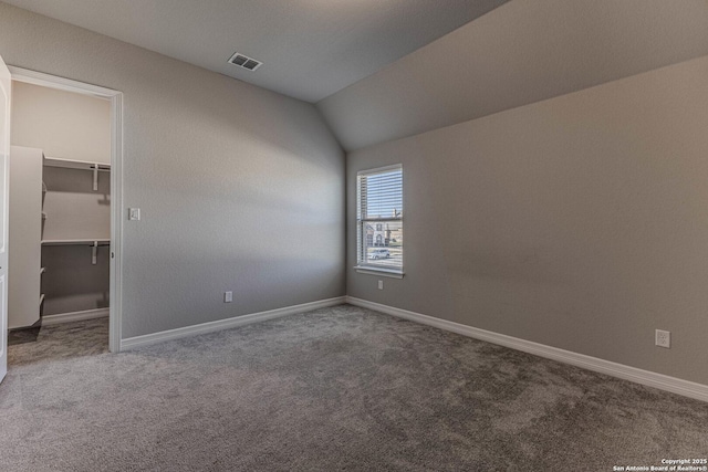 carpeted spare room with vaulted ceiling