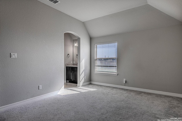 unfurnished living room featuring carpet and vaulted ceiling