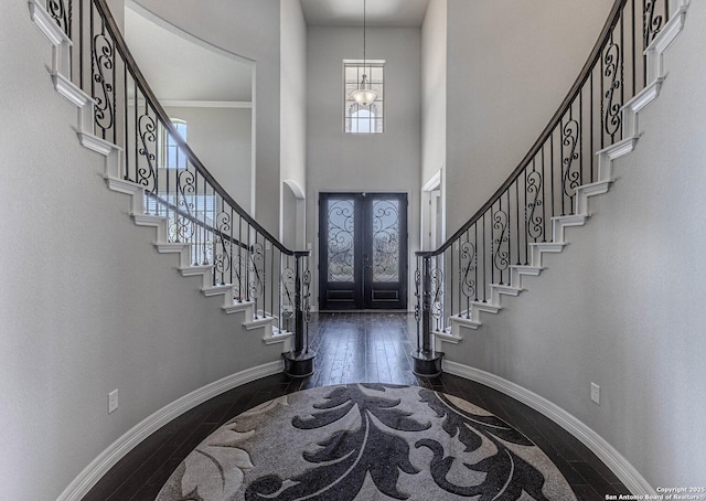 entrance foyer with a high ceiling, dark hardwood / wood-style floors, french doors, and a notable chandelier