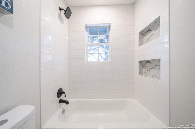 bathroom with toilet and tiled shower / bath combo