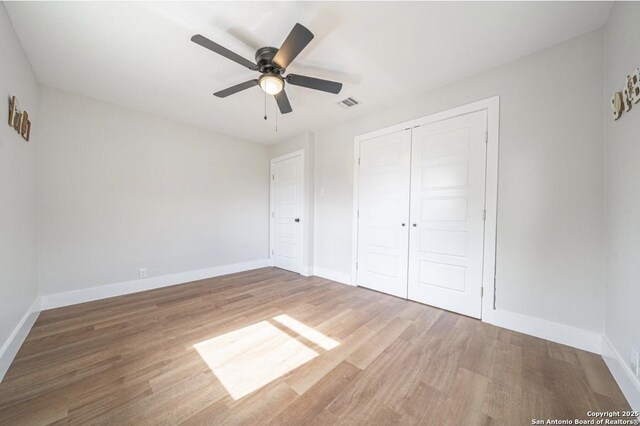 unfurnished bedroom featuring ceiling fan, a closet, and wood-type flooring