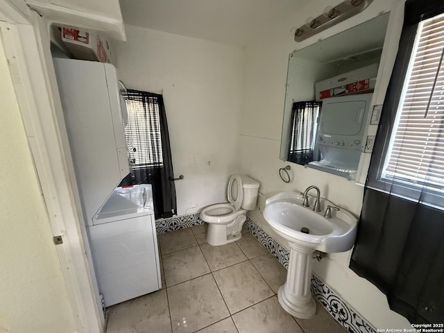 bathroom featuring sink, stacked washer / dryer, tile patterned floors, and toilet