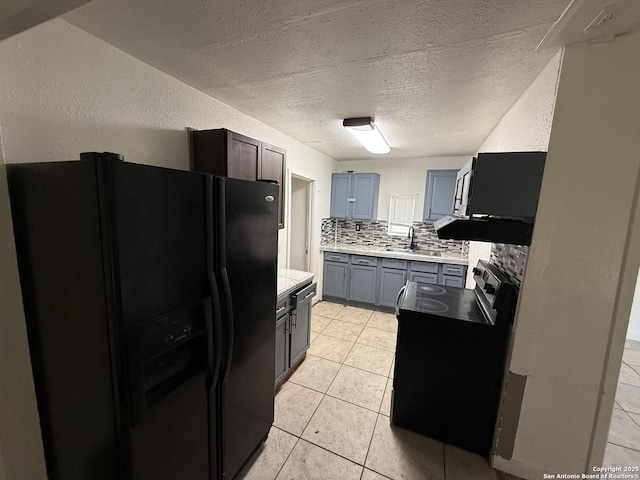 kitchen featuring backsplash, electric range oven, black fridge, sink, and light tile patterned floors