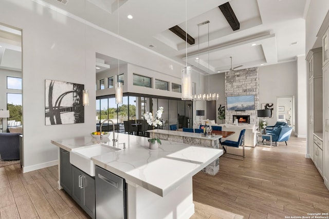 kitchen with decorative light fixtures, a spacious island, a towering ceiling, sink, and light stone countertops