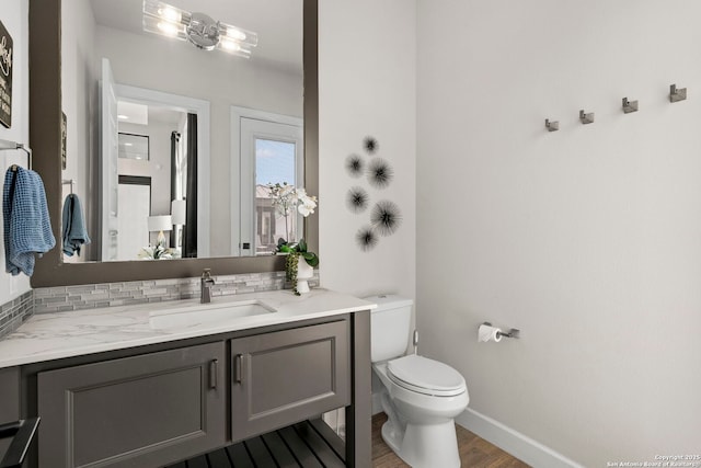 bathroom featuring toilet, vanity, decorative backsplash, and hardwood / wood-style flooring