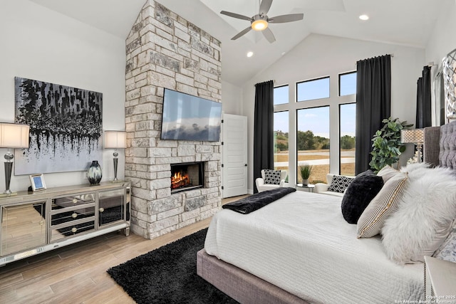 bedroom with ceiling fan, a stone fireplace, and high vaulted ceiling