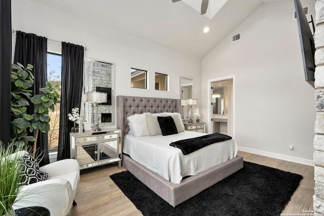 bedroom with light wood-type flooring, ceiling fan, ensuite bathroom, and high vaulted ceiling