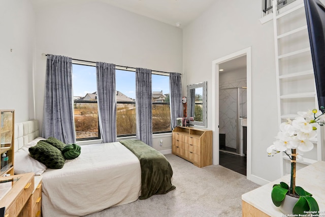 bedroom featuring ensuite bathroom, light colored carpet, and a high ceiling