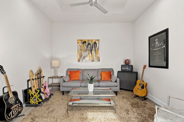 living room featuring ceiling fan, wood-type flooring, and a tray ceiling