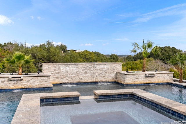 view of swimming pool featuring pool water feature and an in ground hot tub