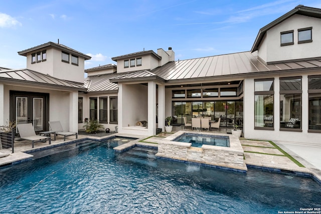 rear view of house with a swimming pool with hot tub and a patio