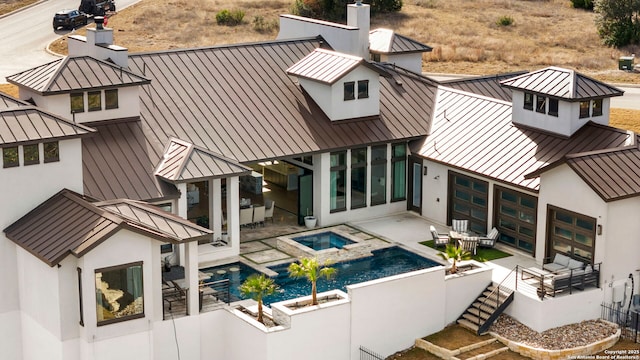 back of house with an in ground hot tub and a patio