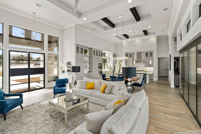 living room with a towering ceiling, ornamental molding, a chandelier, a tray ceiling, and beam ceiling