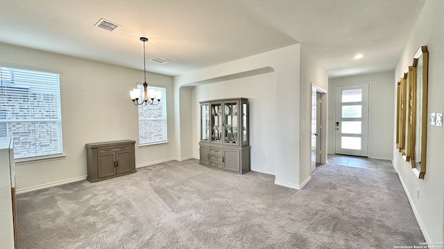 unfurnished dining area featuring light carpet, a wealth of natural light, and an inviting chandelier