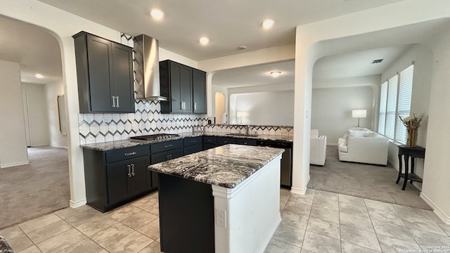 kitchen featuring light carpet, tasteful backsplash, dark stone counters, and wall chimney range hood