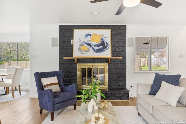 living room featuring ceiling fan, wood-type flooring, ornamental molding, and a fireplace