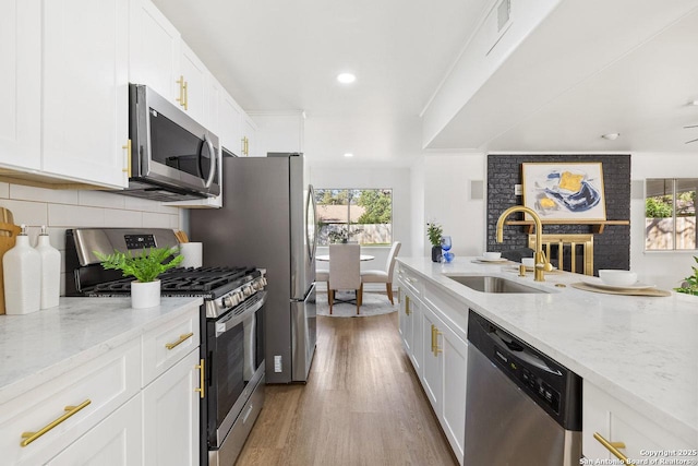 kitchen with light stone countertops, sink, white cabinetry, and stainless steel appliances