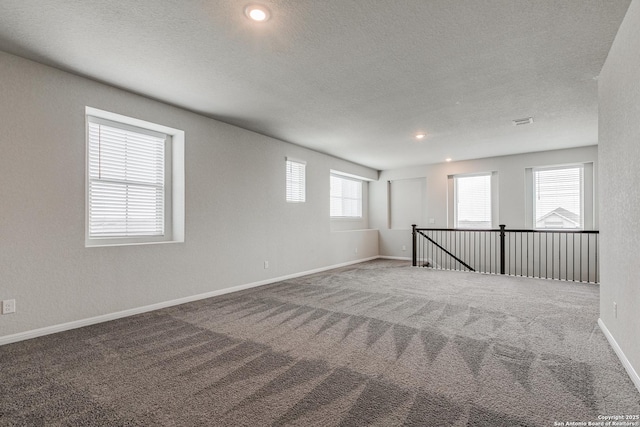 unfurnished room with carpet, a healthy amount of sunlight, and a textured ceiling