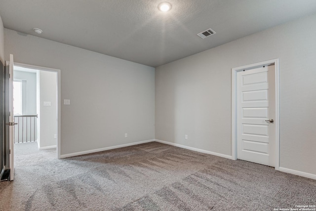 unfurnished room featuring a textured ceiling and carpet flooring