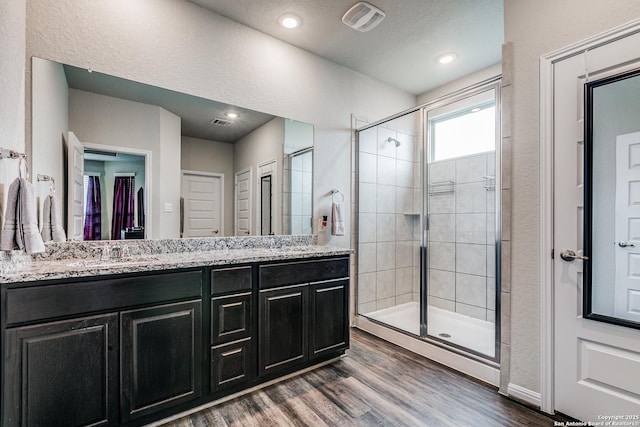 bathroom featuring a shower with shower door, wood-type flooring, and vanity