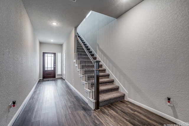 entryway with dark wood-type flooring and a textured ceiling