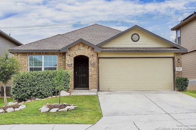 view of front of property with a front yard, a garage, and central AC