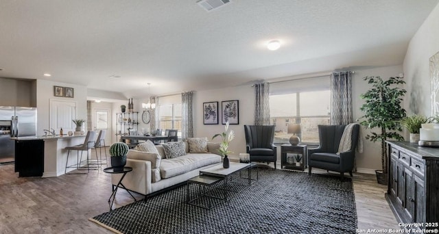 living room with a textured ceiling, dark wood-type flooring, and a chandelier