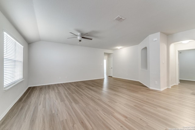 empty room with ceiling fan, vaulted ceiling, a textured ceiling, and light hardwood / wood-style floors