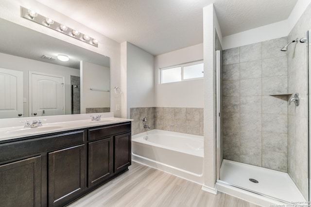 bathroom with vanity, plus walk in shower, a textured ceiling, and hardwood / wood-style floors