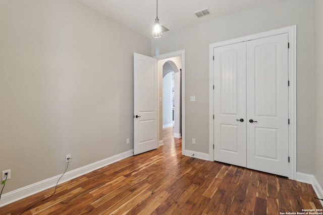 unfurnished bedroom with dark wood-type flooring and a closet