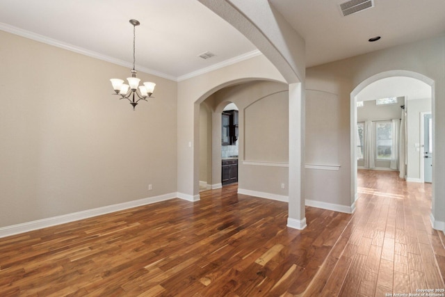 empty room with dark wood-type flooring, ornamental molding, and a chandelier