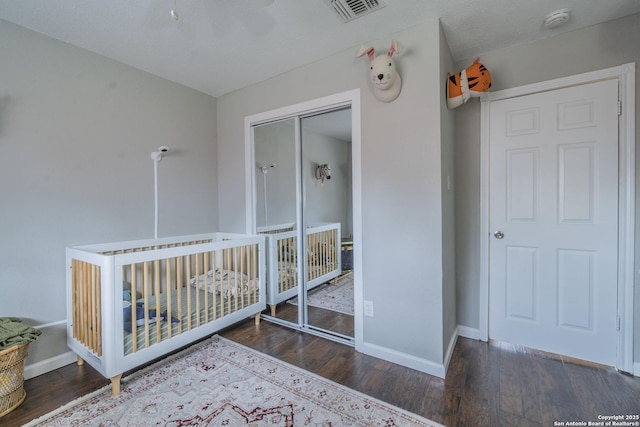 unfurnished bedroom featuring a closet, dark hardwood / wood-style flooring, and a crib