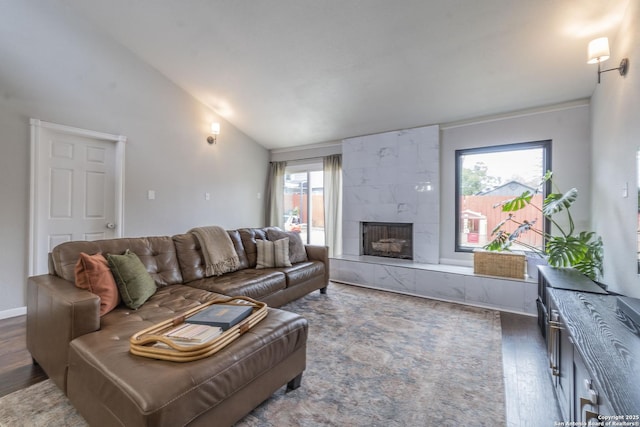 living room with dark wood-type flooring, vaulted ceiling, and a fireplace