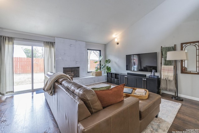 living room featuring lofted ceiling, a tiled fireplace, and dark wood-type flooring