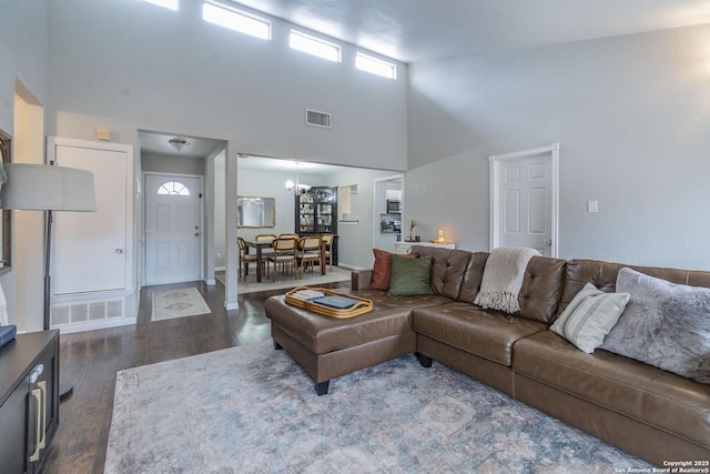 living room featuring an inviting chandelier, dark hardwood / wood-style flooring, and a high ceiling