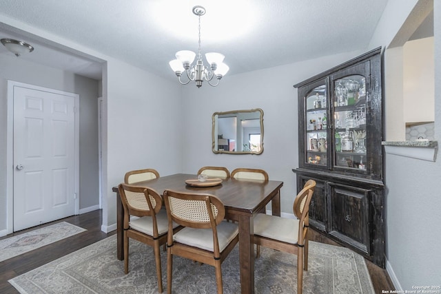 dining area featuring dark wood-type flooring and an inviting chandelier