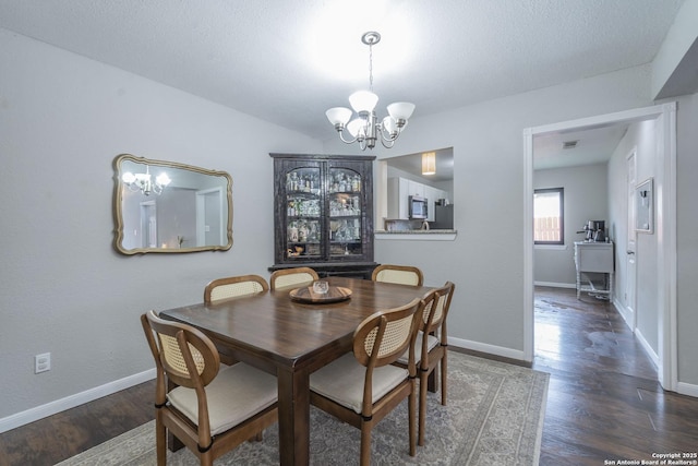 dining area with a textured ceiling, dark hardwood / wood-style floors, and a notable chandelier