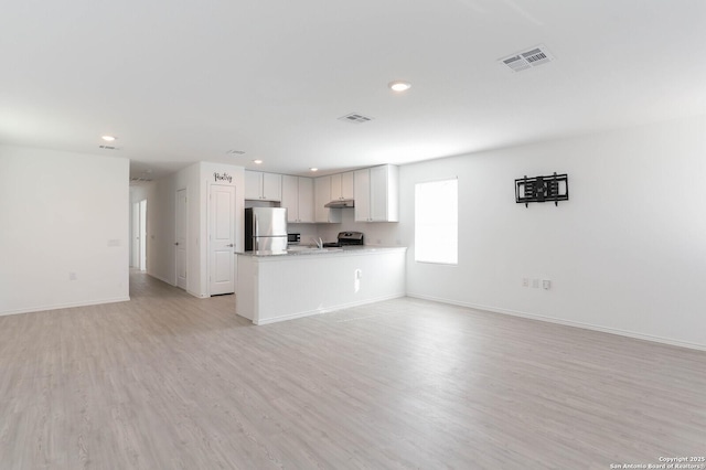 interior space featuring light stone countertops, white cabinets, appliances with stainless steel finishes, kitchen peninsula, and light wood-type flooring