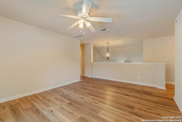 spare room featuring lofted ceiling, ceiling fan with notable chandelier, and light hardwood / wood-style flooring