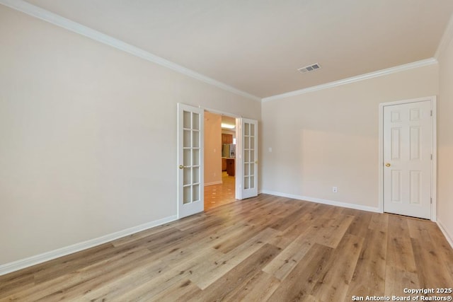 spare room featuring french doors, ornamental molding, and light hardwood / wood-style flooring