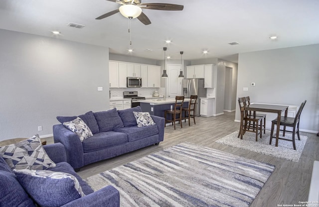 living room with ceiling fan, light hardwood / wood-style flooring, and sink