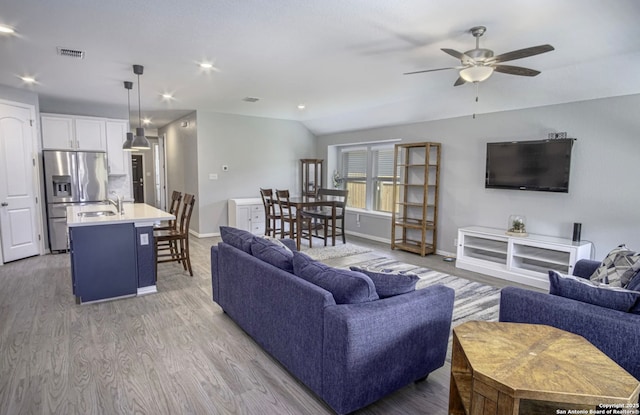 living room featuring lofted ceiling, ceiling fan, sink, and light hardwood / wood-style flooring