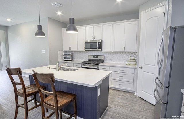 kitchen featuring decorative light fixtures, sink, white cabinets, and appliances with stainless steel finishes