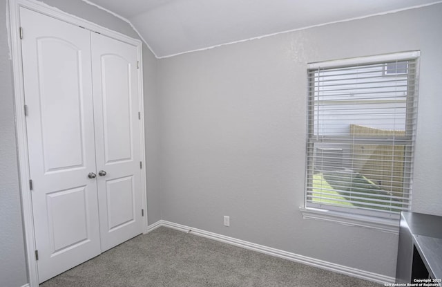 unfurnished bedroom featuring light colored carpet, a closet, and vaulted ceiling