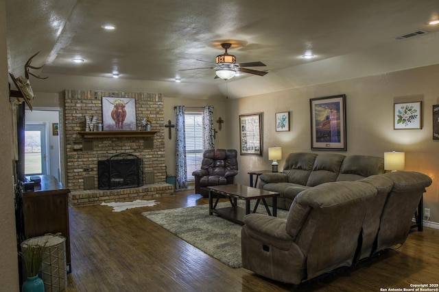 living room featuring dark wood-type flooring, a healthy amount of sunlight, a fireplace, and ceiling fan