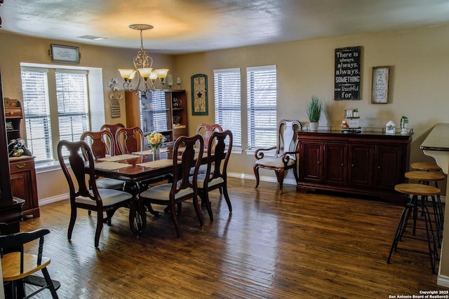 dining room featuring dark wood-type flooring, an inviting chandelier, and plenty of natural light